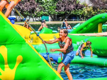 A camper climbing a rope on the atlantis obstacle course.