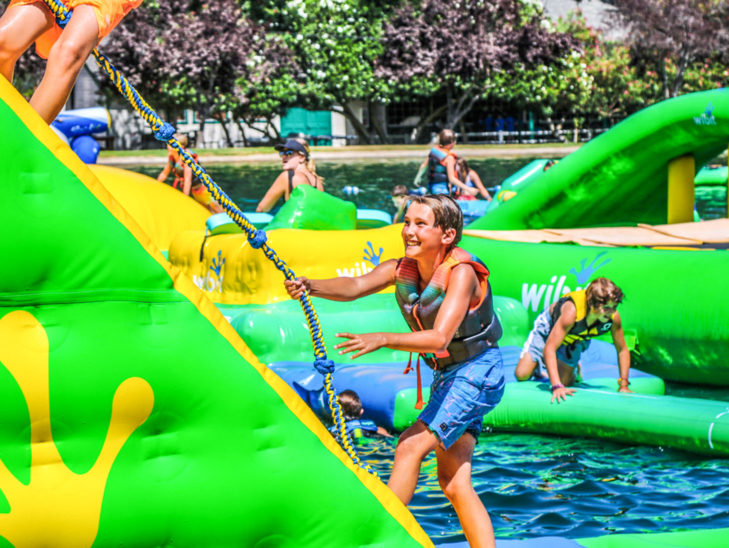 A camper climbing a rope on the atlantis obstacle course.