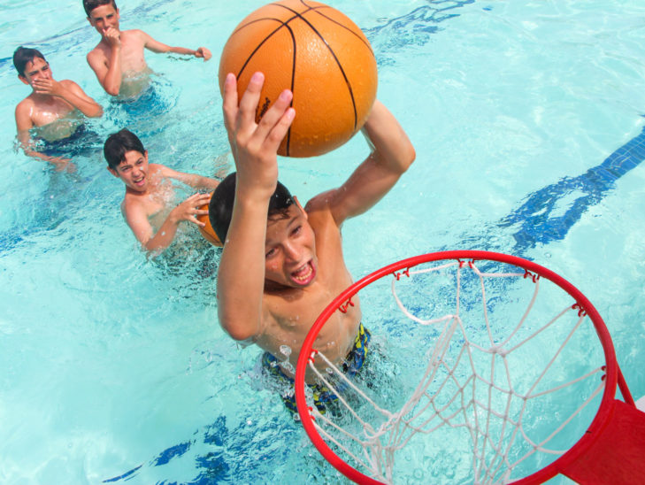 Campers dunking a basketball in the water.