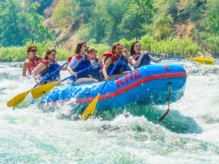 Campers whitewater rafting on a river.