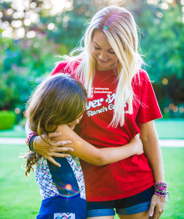 A camper and her family member hugging and smiling.