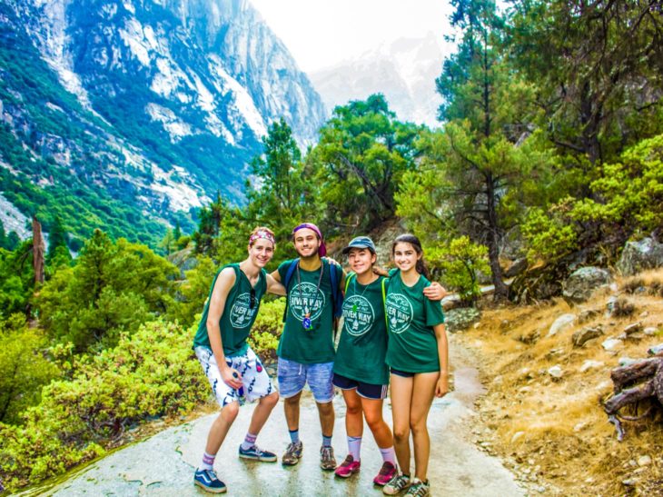 Counselors in training hiking through a mountain trail.