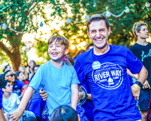 A staff member and a camper smiling.