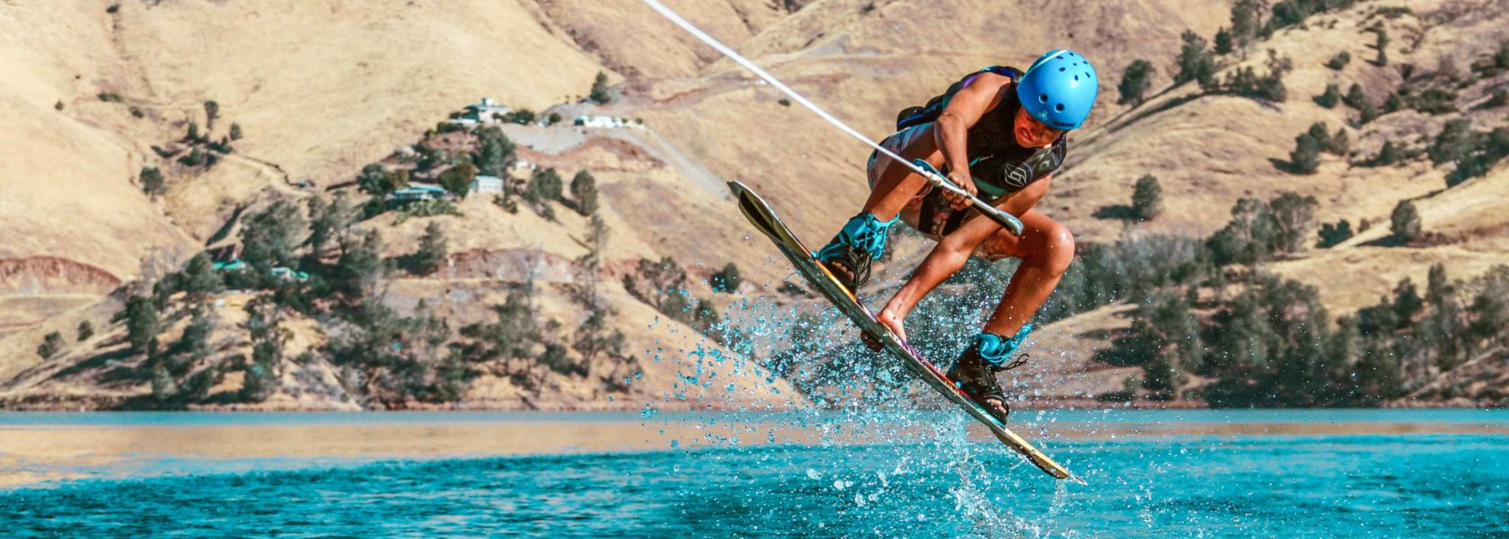 A camper wakeboarding and jumping in the air.